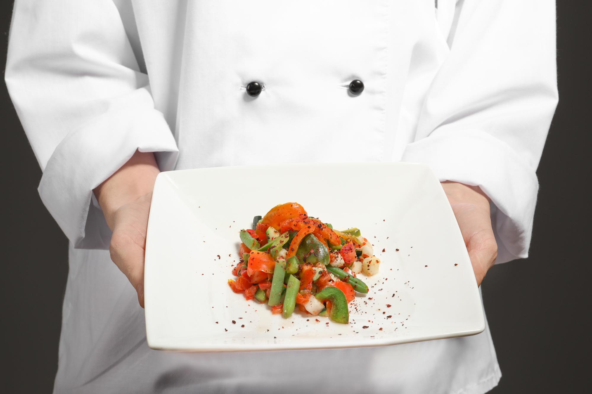 Professional chef plating dish in modern kitchen